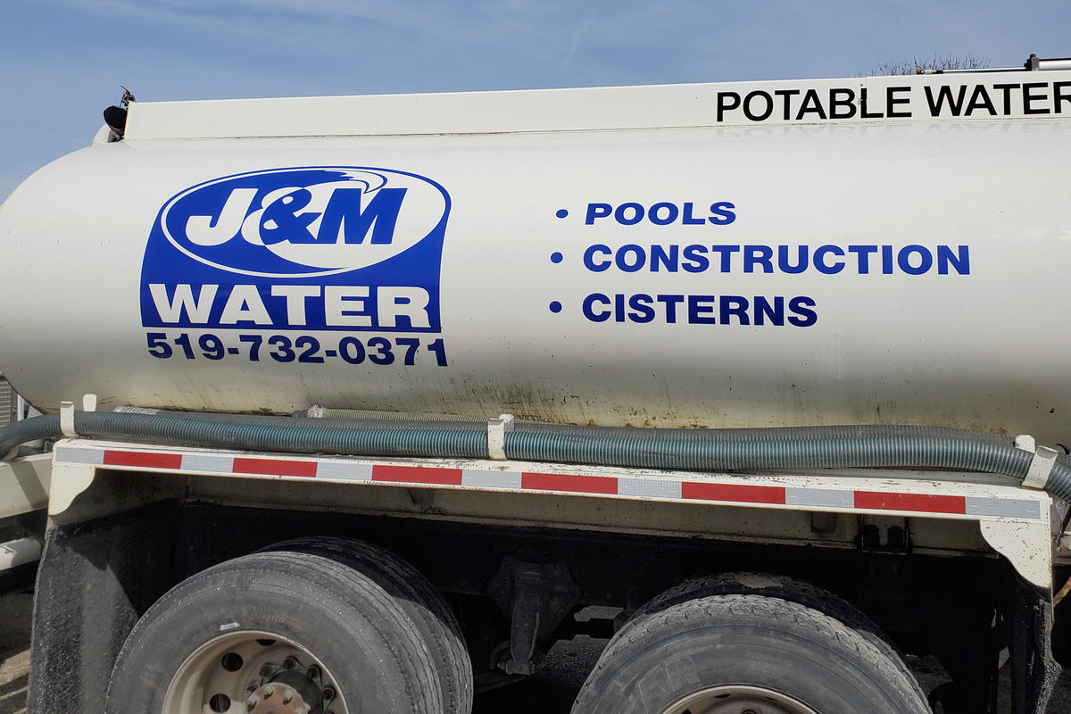 J and M Water Truck Inc. (Brantford) water hauling truck tank with logo, service and phone number listed on the side.